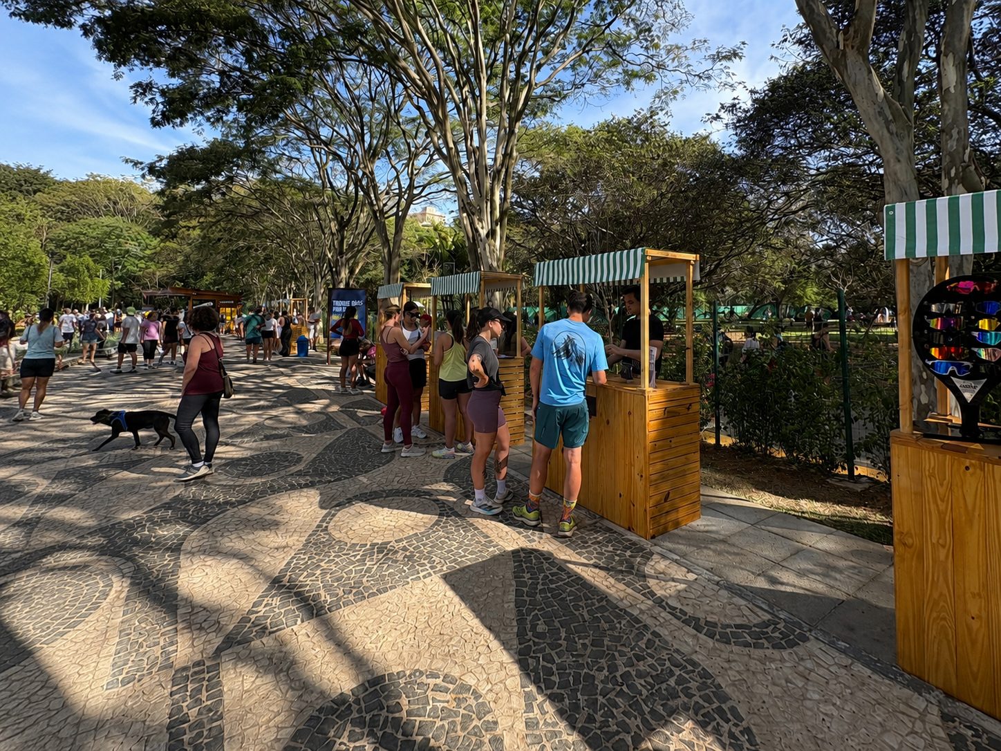 Visitantes circulando entre as barracas de madeira durante a feira