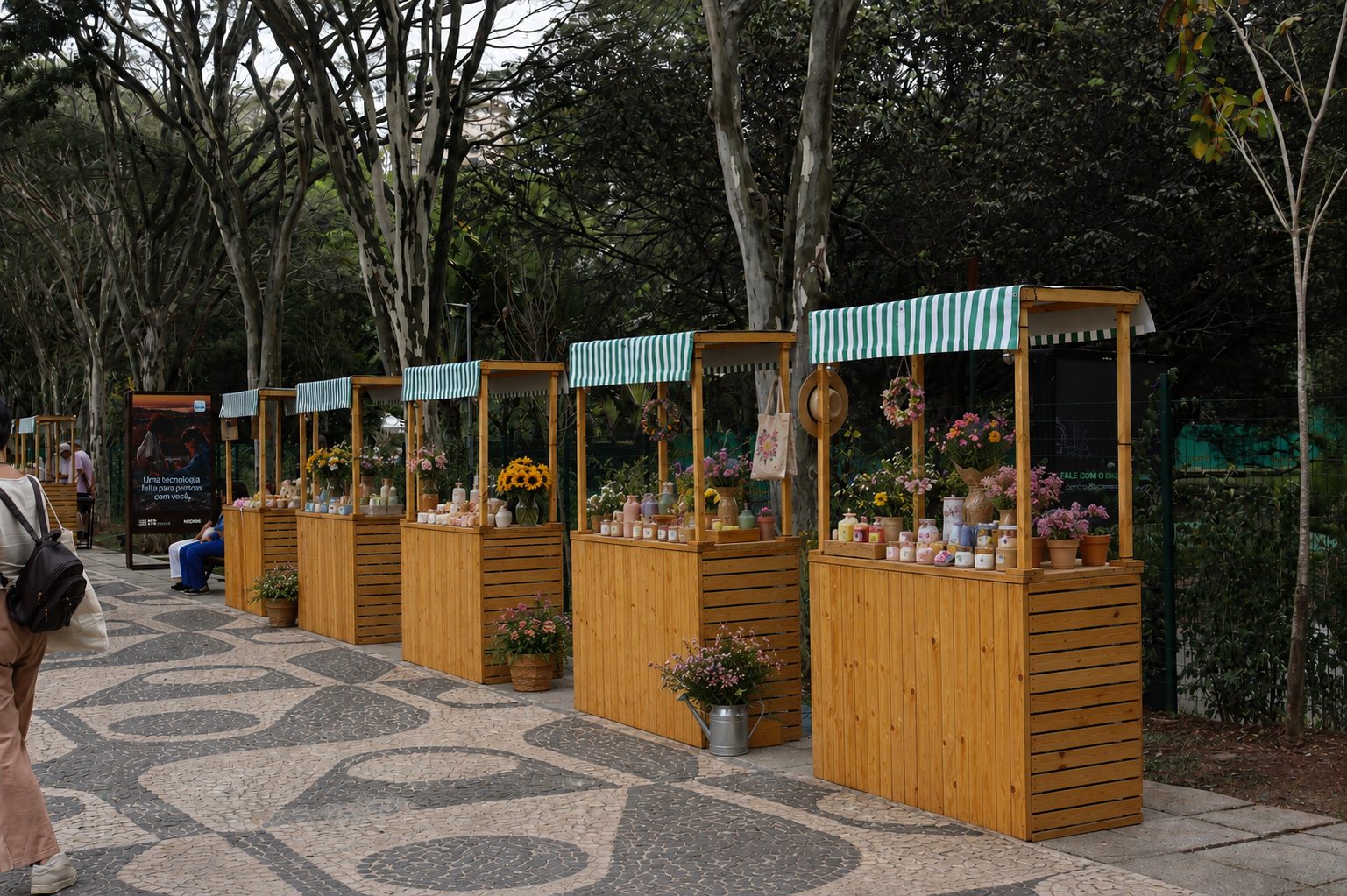 Fileira de barracas de madeira com toldos listrados verde e branco decoradas com flores no Parque Villa-Lobos